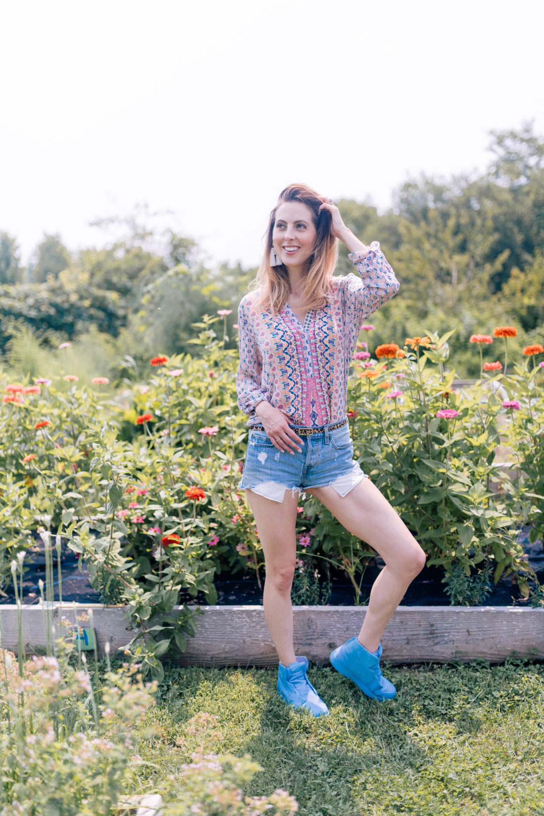 Eva Amurri Martino wears denim cutoffs and a printed top and stands in the garden of a local connecticut farm