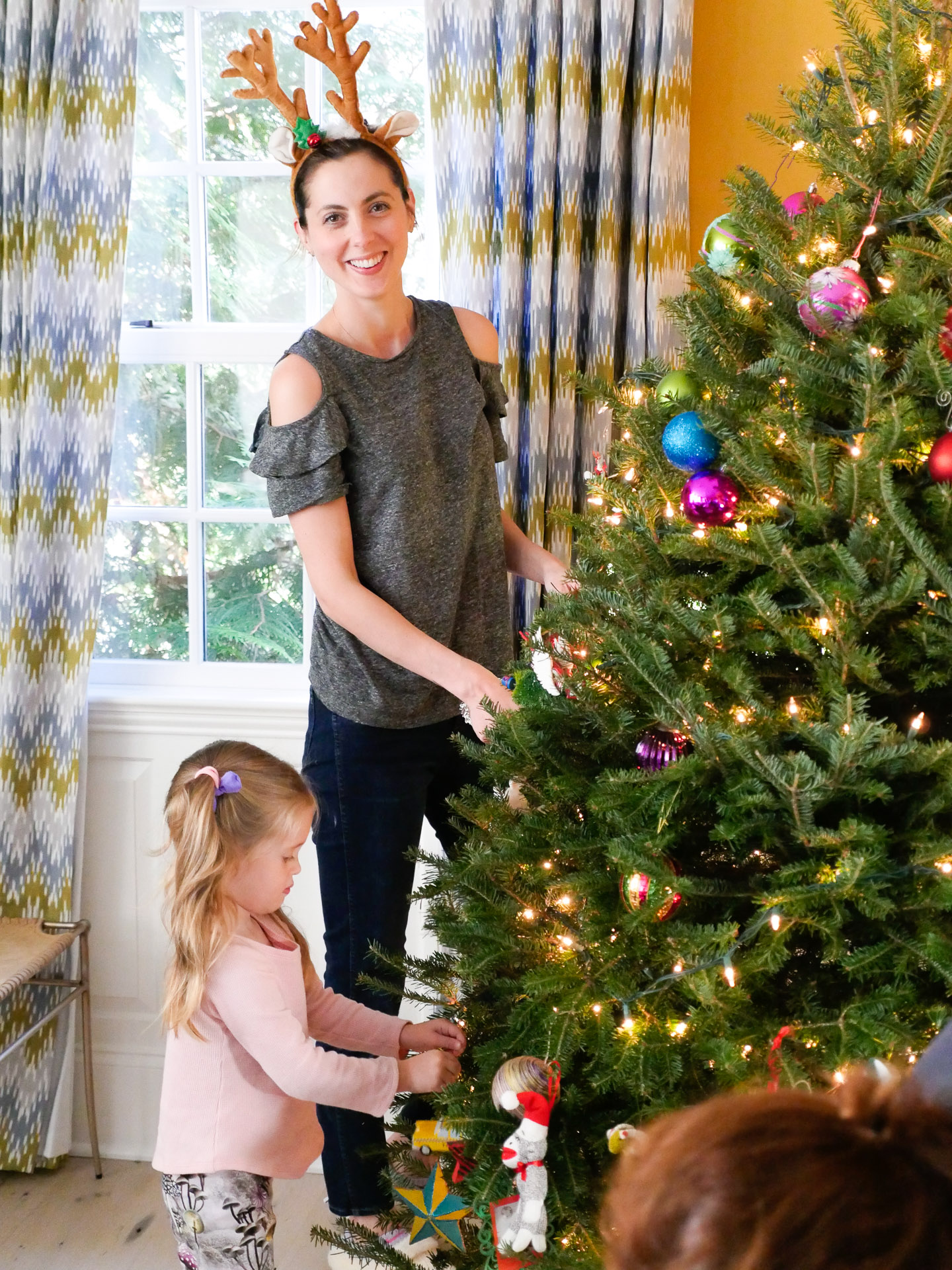 Eva Amurri wears reindeer antlers and decorates her Christmas tree with her family using a variety of ornaments collected over the years as a Christmas tradition for kids
