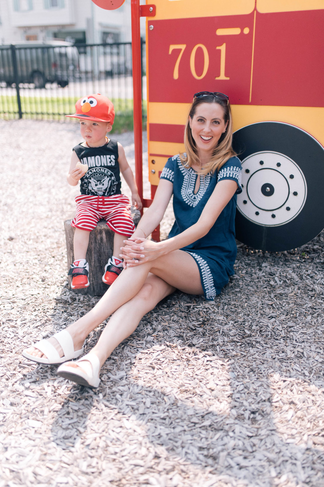 Eva Amurri Martino sits on the ground wearing a navy blue dress, while son Major snacks on a stool next to her