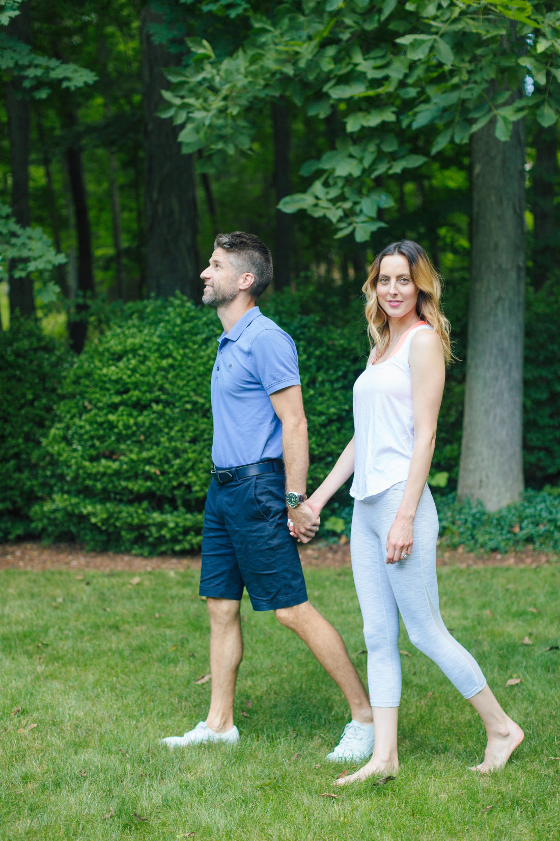 Eva Amurri Martino and Kyle Martino hold hands while wearing active wear, and strolling through the grounds of their Connecticut home