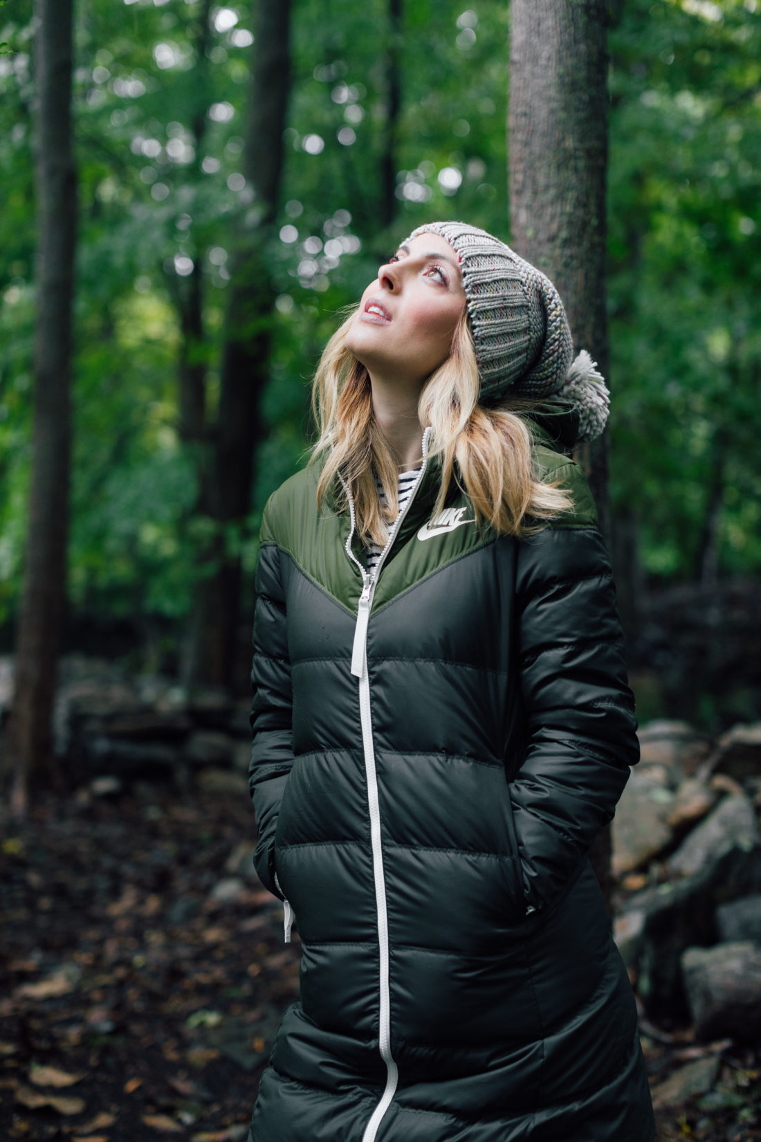 Eva Amurri Martino wears a puffy jacket and a grey knit hat and stands in the woods in Connecticut