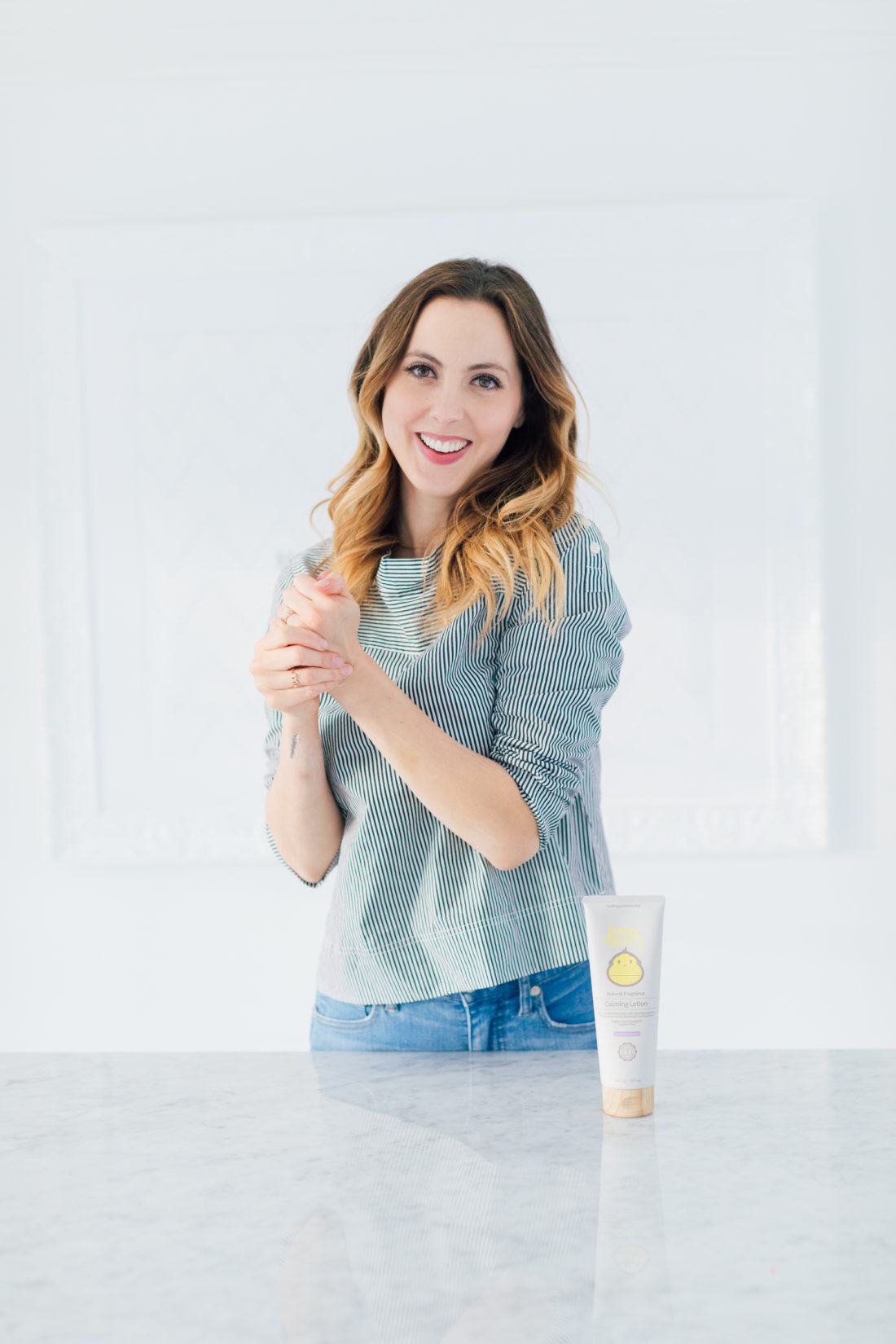 Eva Amurri Martino wears a striped boatneck top, and uses baby bum calming lotion to moisturize her hands and arms
