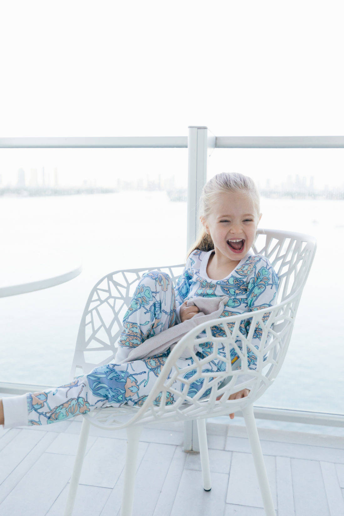 Marlowe Martino relaxes on the balcony in Miami wearing her buggy pajamas from the Happily Eva After x Masala Baby capsule collection