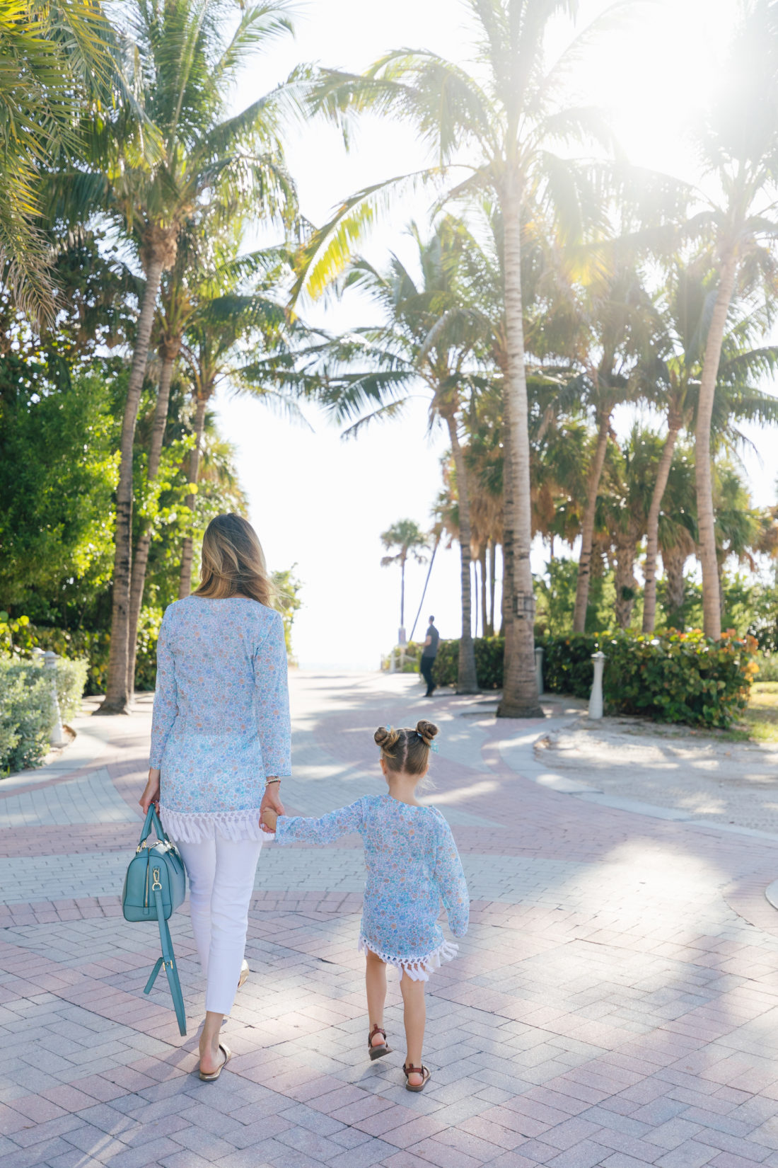 Eva Amurri Martino and Marlowe Martino walk together towards the beach in Miami wearing matching floral fringe tunics from the Happily. Eva After x Masala Baby capsule collection
