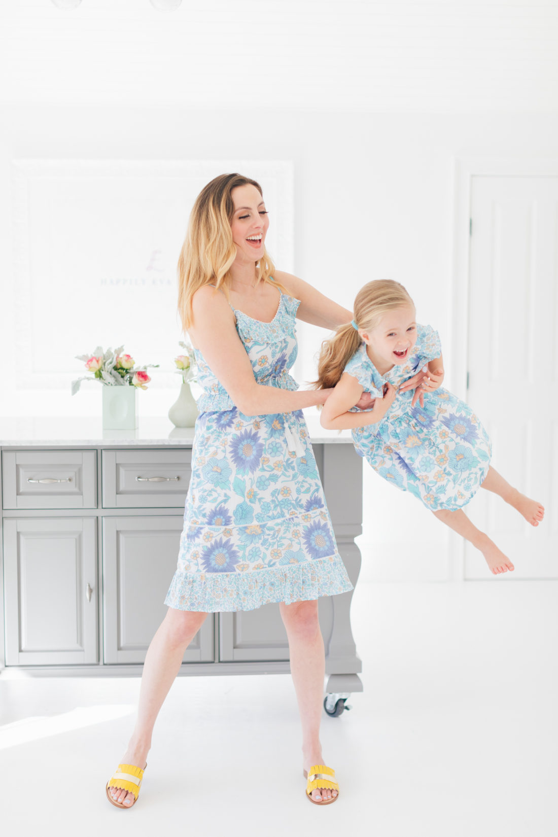 Eva Amurri Martino swings daughter Marlowe in her arms while wearing matching floral printed dresses from the Happily Eva After x Masala Baby capsule collection