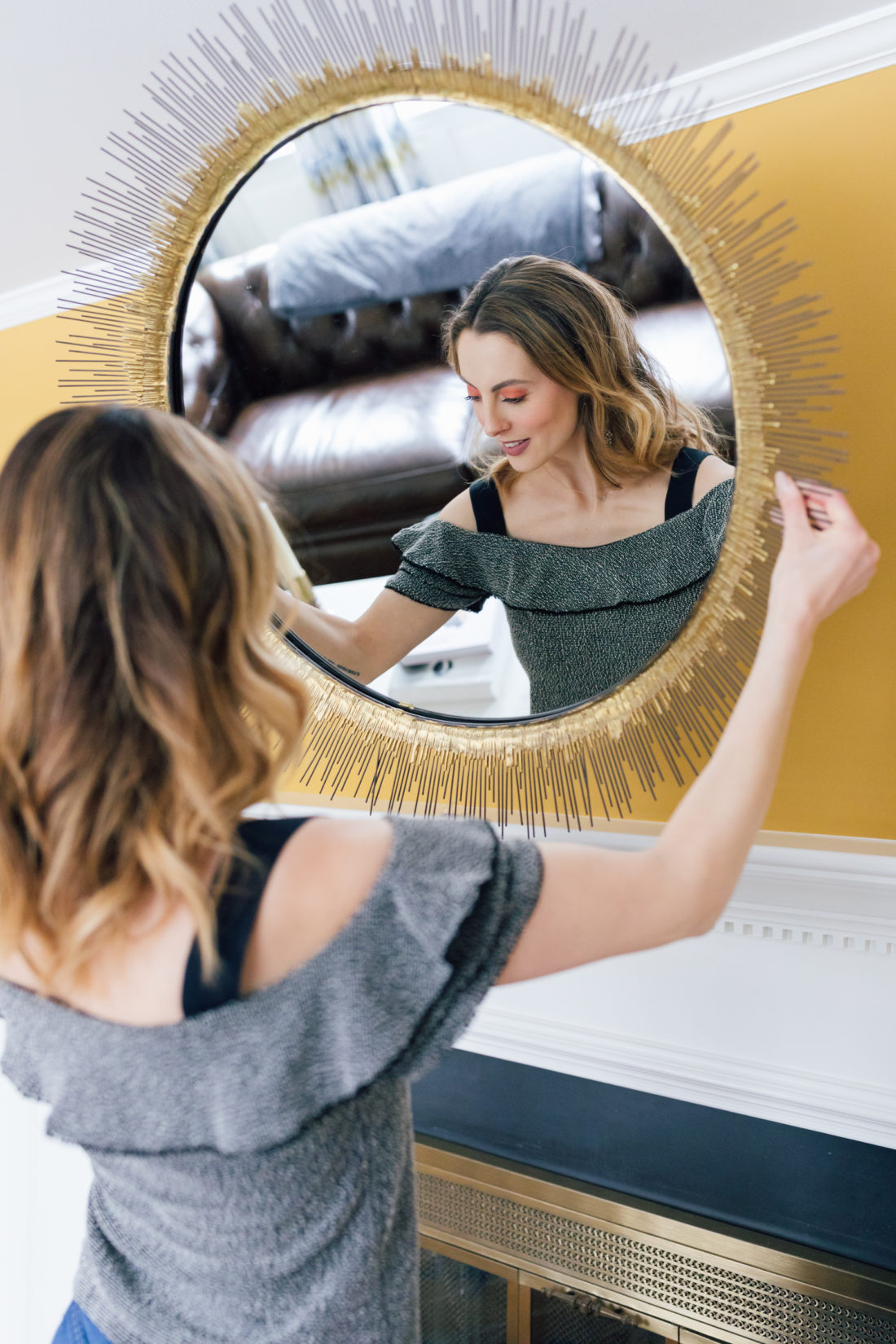 Eva Amurri Martino wears an off the shoulder ruffle top, and takes a starburst mirror off of the wall in her connecticut home