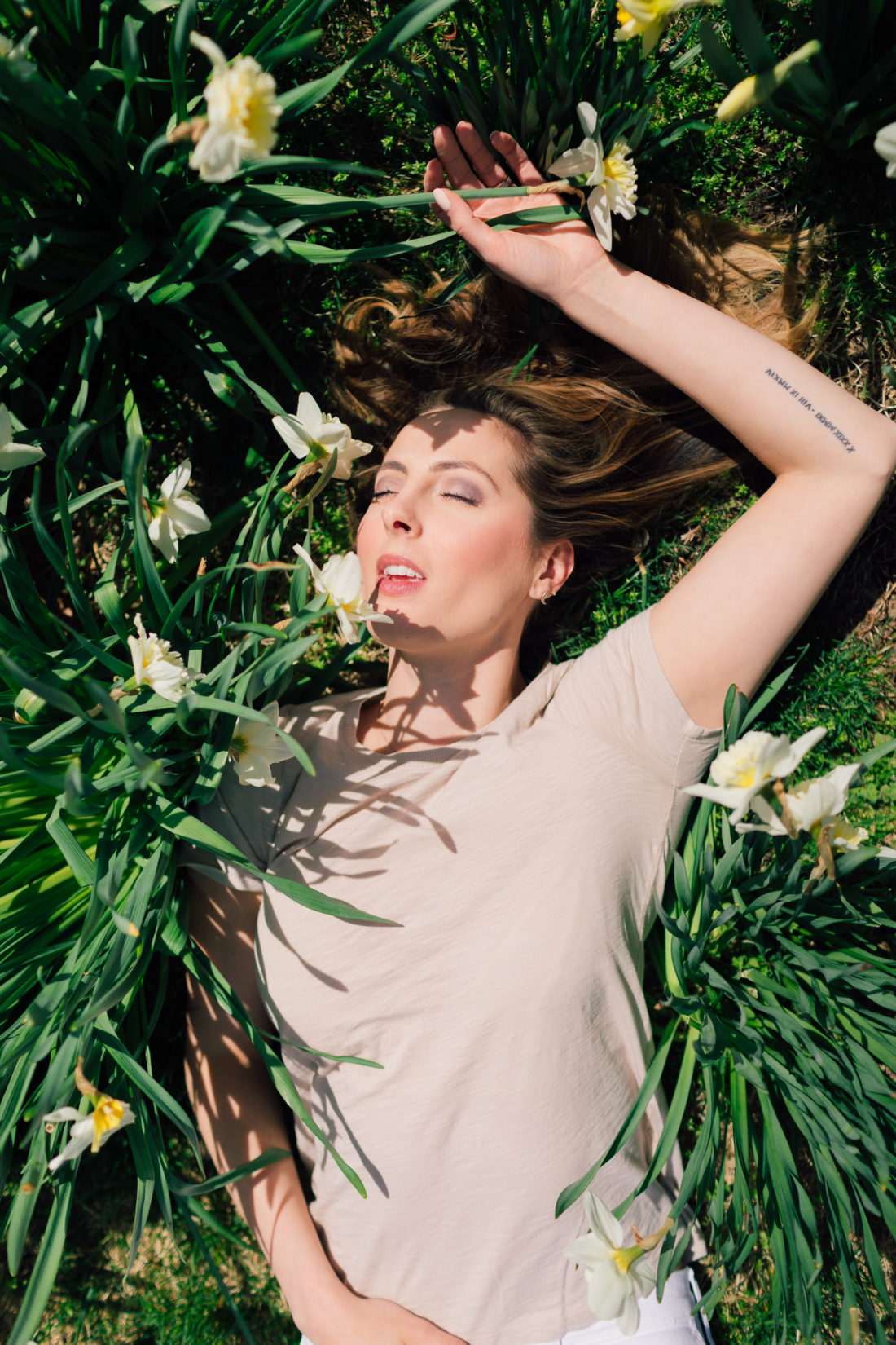 Eva Amurri Martino of Happily Eva After lies in a pile of daffodils and shares her favorite nude colored pieces for spring