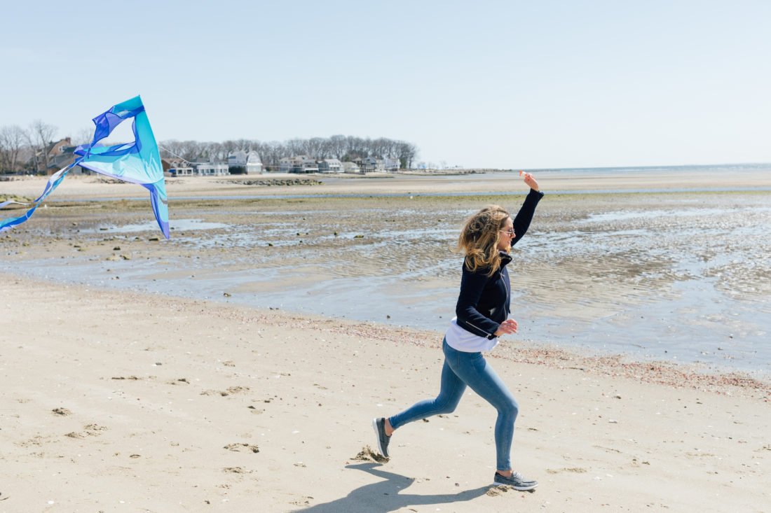 Eva Amurri Martino of Happily Eva After wears Sketchers GoWalk Lite Isla Boat Shoe while flying a kite on the beach