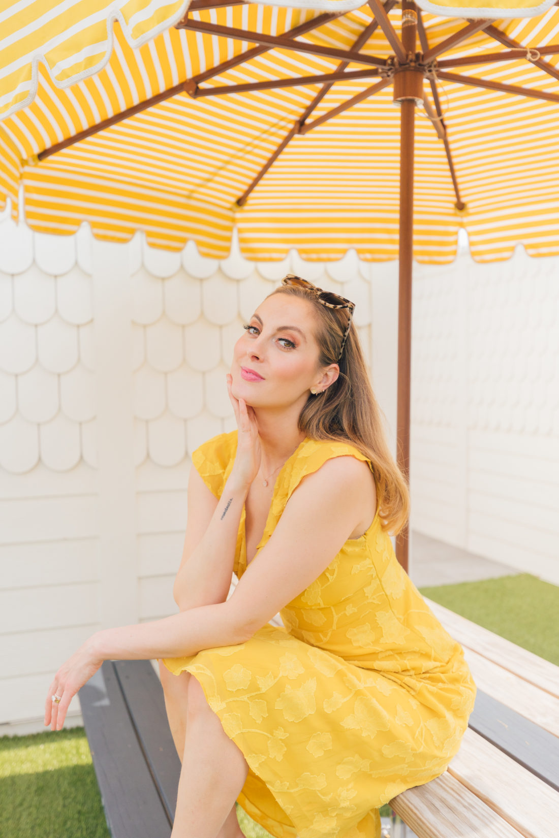 Eva Amurri Martino wears a bright yellow dress next to a yellow striped umbrella