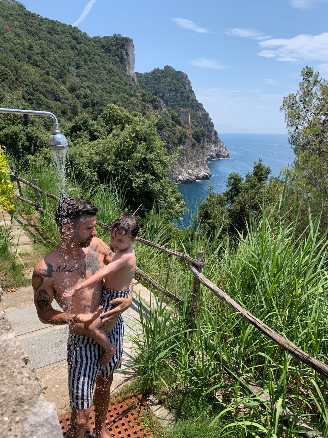 Kyle Martino holds son Major under an outdoor shower in the Amalfi Coast