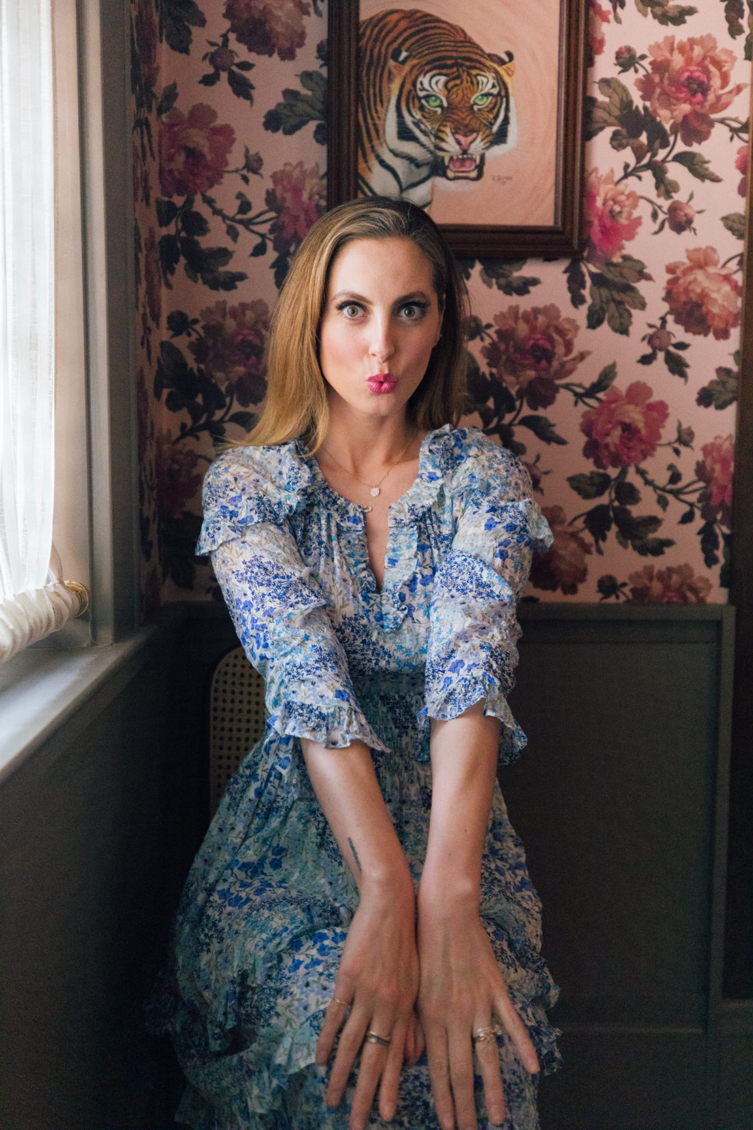 Eva Amurri Martino sits in a floral dress in front of peony wallpaper at the Clermont Hotel
